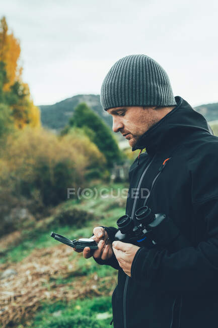 Молодой кавказский человек с биноклем в горах осенних цветов — стоковое фото