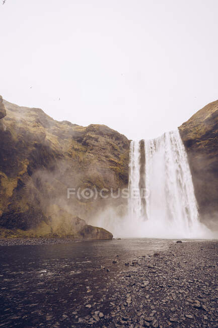 Cascade d'eau tombant dans la rivière entre les rochers en Islande — Photo de stock