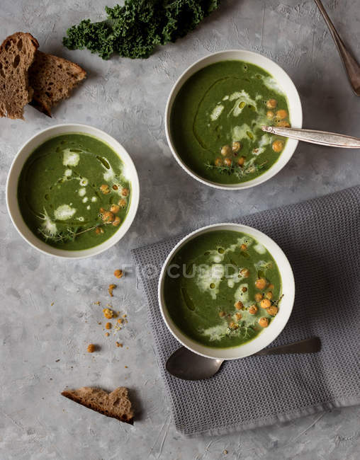 Миски зі шпинатом, капустою та вершковим супом з фенхелю на сірій поверхні — стокове фото