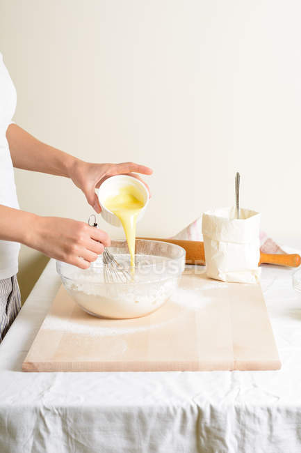 Обрізаний жінкою, що поливає масло в мисці на кухні . — стокове фото