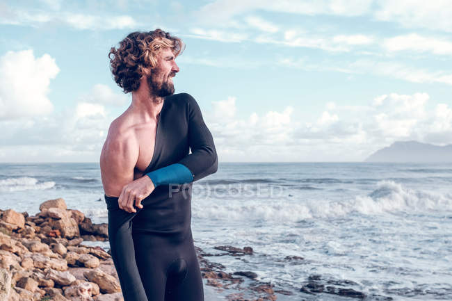 Jovem barbudo vestindo roupa de mergulho perto do oceano — Fotografia de Stock