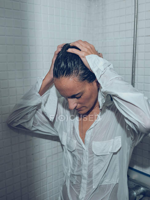 Junge nasse Frau im Hemd steht in der Dusche — Stockfoto