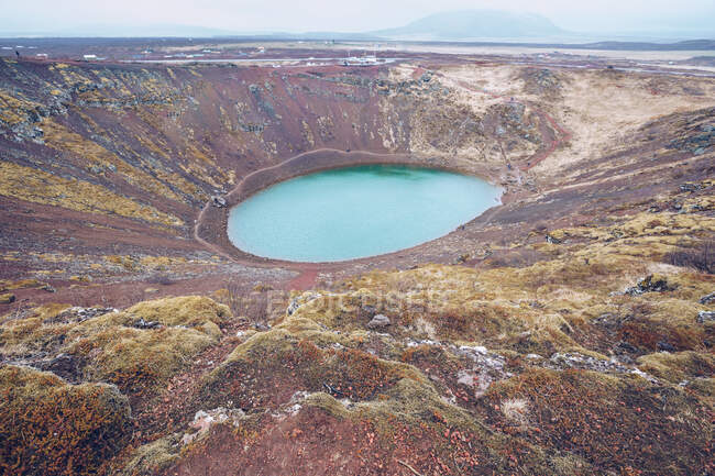 Du dessus du lac dans le cratère entre les terres brunes de la mort et les collines avec ciel ? dans les nuages en Islande — Photo de stock