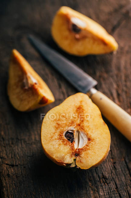 Fruit de coing fraîchement coupé sur fond bois foncé avec couteau — Photo de stock