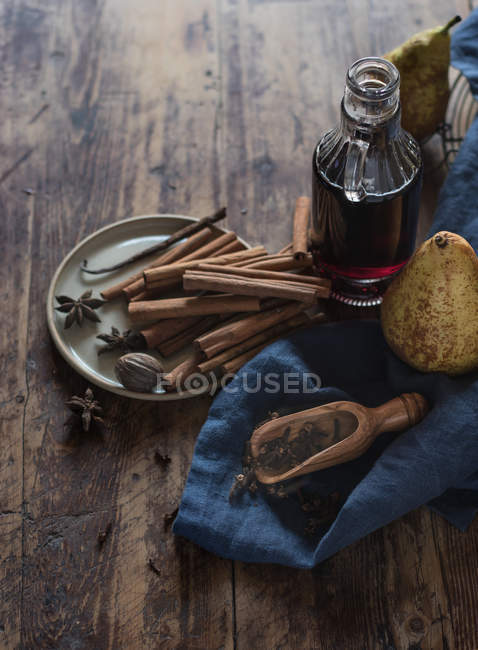 From above of ripe pears near bottle of red wine and plate with assorted aromatic spices on timber tabletop — Stock Photo