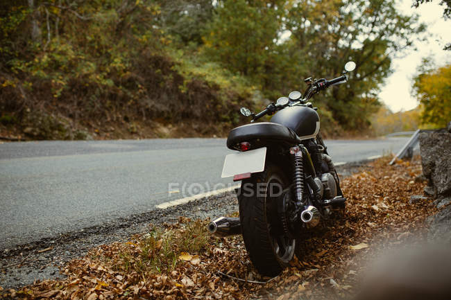 Café piloto de moto estacionado na estrada no campo de outono — Fotografia de Stock