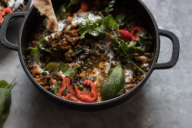 Pentola di ragù con lenticchia e curry di patate dolci su tavolo grigio — Foto stock
