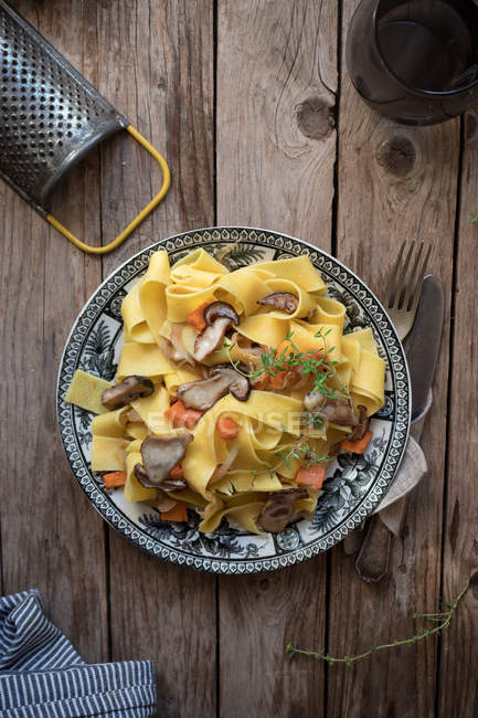 Plate of prepared pappardelle spaghetti with pumpkin and boletus on wooden table — Stock Photo