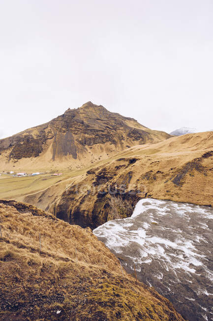Rio de montanha com cascata de água entre colinas de pedra marrom e vista na Islândia — Fotografia de Stock