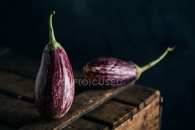 Fresh eggplants on wooden table on dark background — Stock Photo