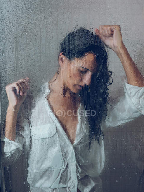 Sopping mujer en camisa de pie en cabina de ducha - foto de stock