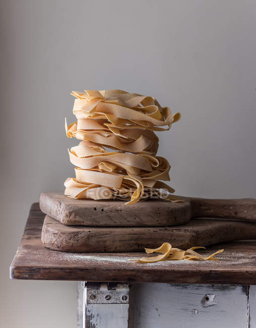 Pile of wheat pappardelle spaghetti on old wood table on grey background — Stock Photo