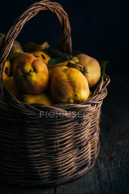 Marmelos frescos colhidos em cesta no fundo de madeira escura — Fotografia de Stock