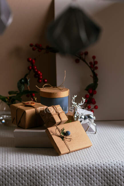 Boîtes cadeaux, enveloppées dans du papier recyclé, empilées sur la table de fête décorative — Photo de stock