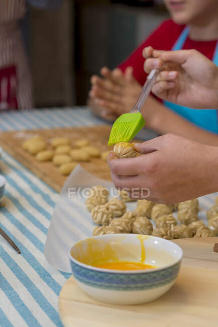 Trabajar en pastelería tradicional pintada con huevo antes de hornear - foto de stock