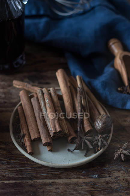 Close-up of ceramic plate with heap of various spices on lumber tabletop near blue napkin — Stock Photo