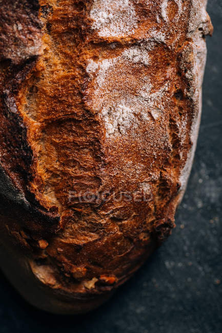 Primer plano de pan rústico casero sobre fondo oscuro - foto de stock