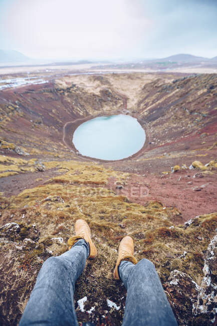 De cima da colheita pernas humanas perto do lago na cratera entre a morte terras marrons e colinas na Islândia — Fotografia de Stock