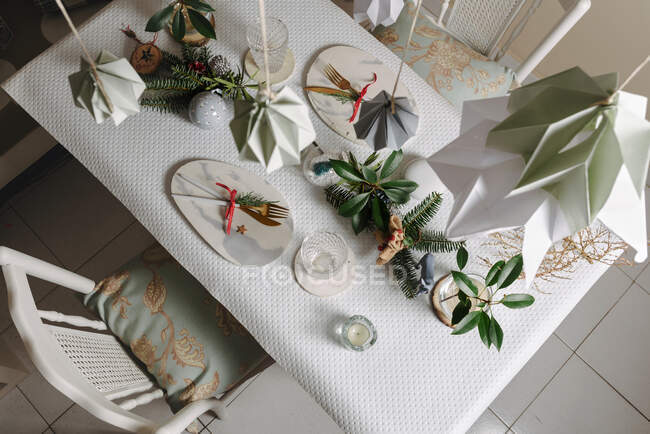 Table sertie de blanc doré à Noël. Chaises blanches vintage et décorations suspendues décorant la table — Photo de stock