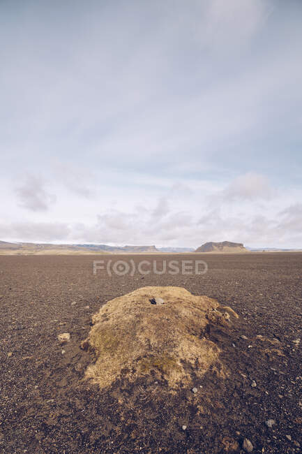 Desde arriba montaña marrón con cráter entre oscuros terrenos silenciosos y cielo azul hermoso en Islandia - foto de stock