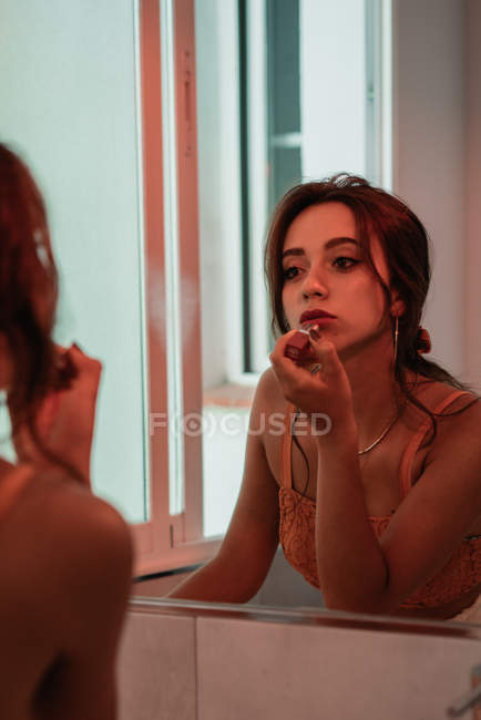 Отражение страстной привлекательной брюнетки с помадой перед зеркалом — стоковое фото