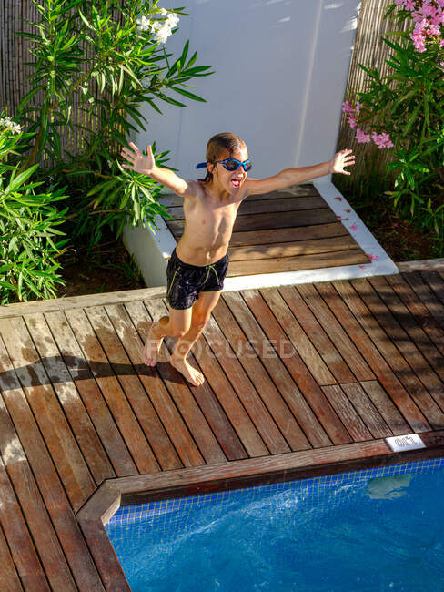 Захоплений хлопчик біжить до басейну — стокове фото