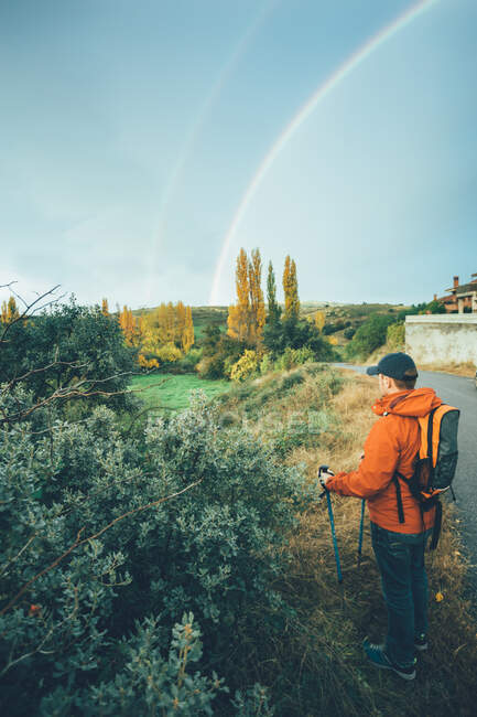 Wanderer auf einem Wanderweg in Herbstfarben mit einem doppelten Regenbogen am Himmel — Stockfoto