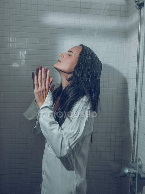 Donna vestita bagnata in piedi nella doccia sotto l'acqua spruzzante — Foto stock