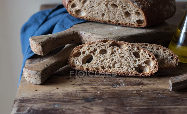 Tranches de pain complet frais de kamut avec de l'épeautre et de la bière sur une table en bois — Photo de stock