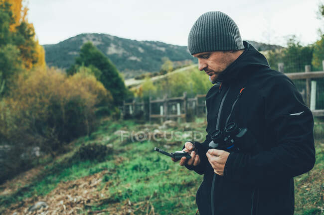 A young caucasian man with binoculars in te mountain in autumn colors — Stock Photo