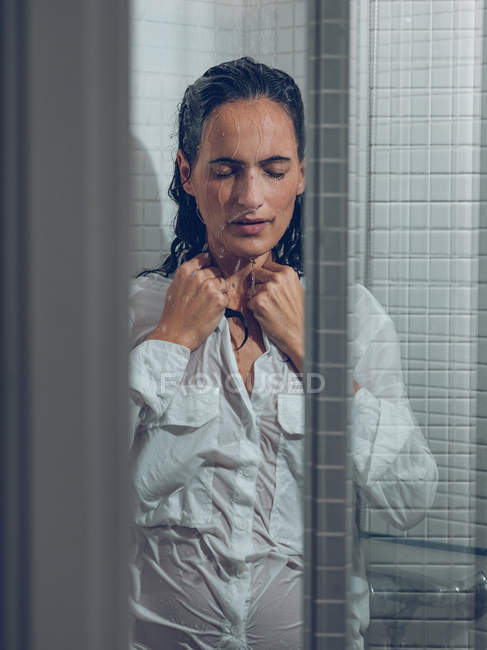 Donna vestita bagnata in piedi nella doccia sotto l'acqua spruzzante — Foto stock