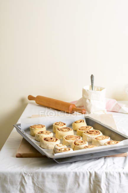 Pequenos pães crus na assadeira na mesa da cozinha . — Fotografia de Stock