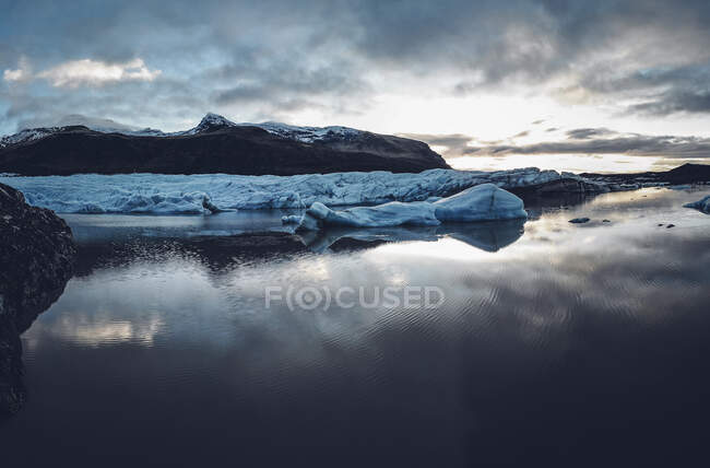 Montañas con picos nevados reflejados en el agua - foto de stock