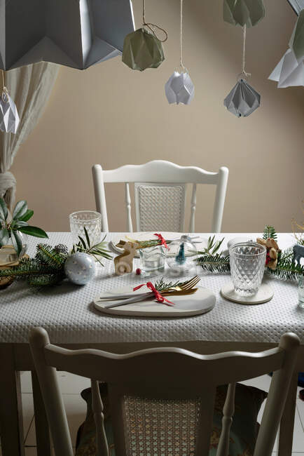 Накрытие праздничного стола в белых и золотых тонах, с висячими украшениями, украшающими стол — стоковое фото