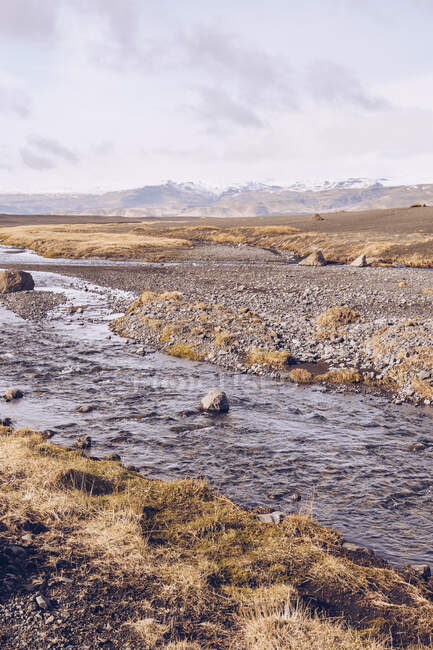 Fiume di montagna che scorre tra terreni marroni e vista sulla pianura in Islanda — Foto stock