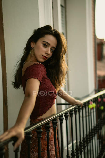 Porträt einer charmanten jungen brünetten Dame, die auf dem Balkon posiert — Stockfoto