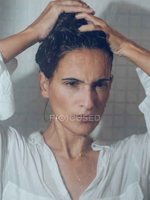 Sopping woman in shirt posing in shower cabin — Stock Photo