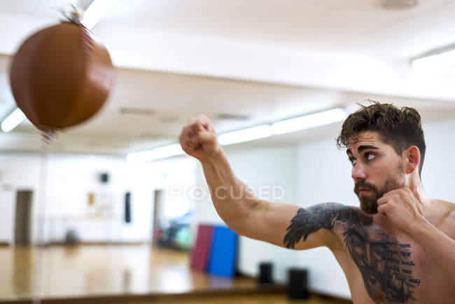 Junger Mann trainiert in Turnhalle mit Boxsack — Stockfoto