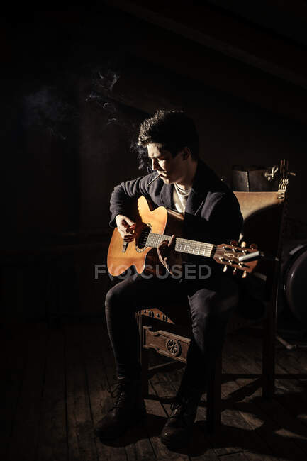 Hombre con guitarra y cigarrillo sentado en sillas - foto de stock