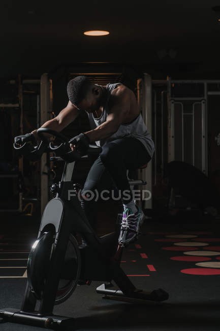 Hombre negro serio en bicicleta estática en el gimnasio - foto de stock