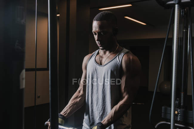 Negro musculoso hombre ejercitando en oscuro gimnasio - foto de stock
