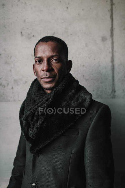 Portrait of African American man in stylish warm clothes standing against concrete wall — Stock Photo