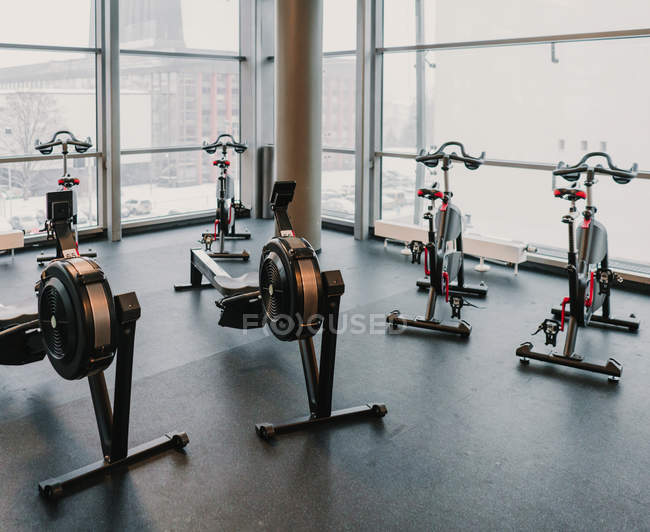 Various modern exercise machines standing near large window inside amazing stylish gym — Stock Photo