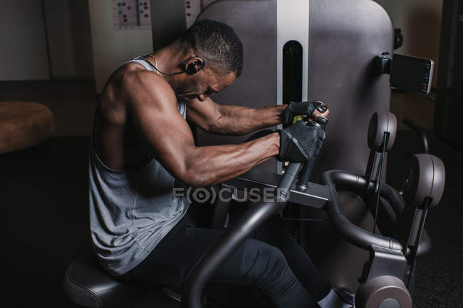 Preto homem exercitando no máquina no ginásio — Fotografia de Stock