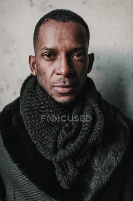 Bonito homem afro-americano em roupas quentes elegantes que estão perto da parede de concreto — Fotografia de Stock