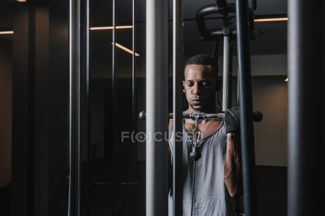 Hombre negro haciendo ejercicio en la máquina - foto de stock