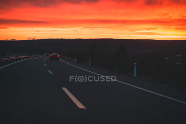 Fahrzeuge, die bei Sonnenuntergang die Landstraße entlang fahren, in Erbsencape, asturien — Stockfoto