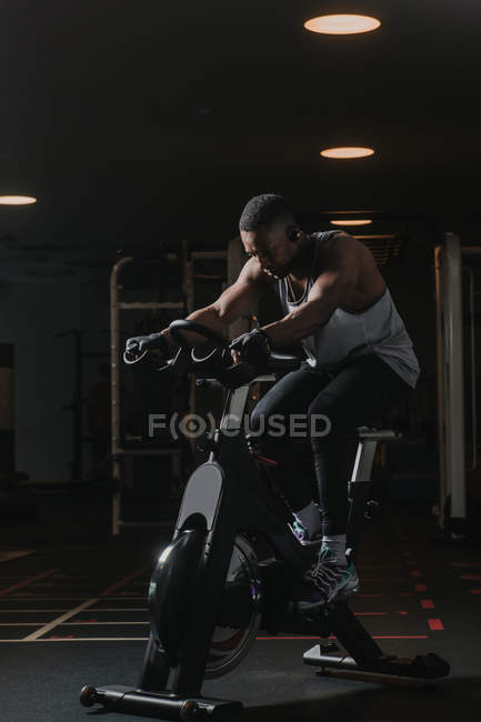 Серьезный черный мужчина на велотренажере в спортзале — стоковое фото