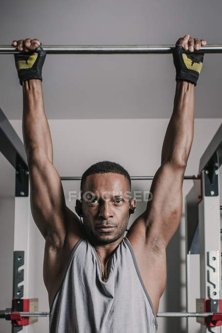 Black guy hanging on bar in gym — Stock Photo