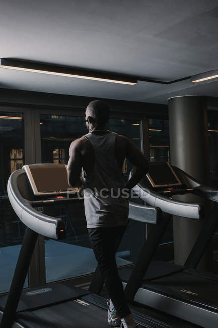 Чорний чоловік біжить на біговій доріжці в спортзалі — стокове фото